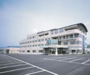 介護施設の建物外観。白と黒を基調とした3階建て高齢者向け施設の全景。